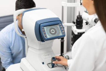 Optometrist checking patients vision at modern clinic