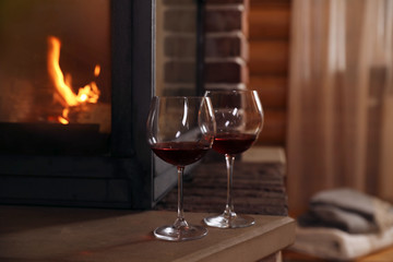 Glasses of wine near fireplace indoors. Winter vacation