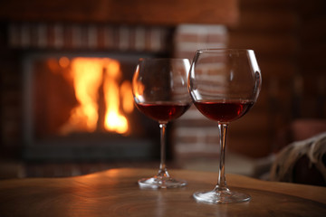 Glasses of wine blurred fireplace on background, space for text. Winter vacation