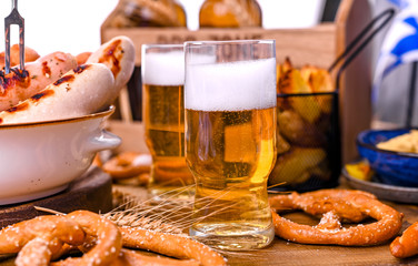 Fresh beer with foam on a wooden background. Oktoberfest German Pretzels.