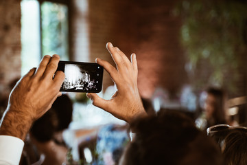 photo of a man filming a wedding on his phone