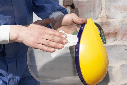 a man wipes a protective glass on a plastic face mask close-up, yellow color. protection against the spread covid-19