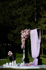 against the background of the forest there is a pink arch for weddings of newlyweds, a festive decor with decorations from the vets, pink fabric crumbles the arch,