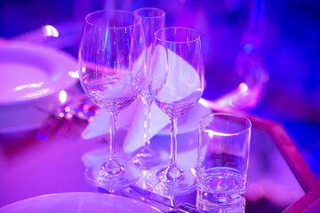 in pink light are glasses on the table, beautiful festive table setting