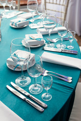 on the table with a blue tablecloth there is dishes, a festive table setting in restran,