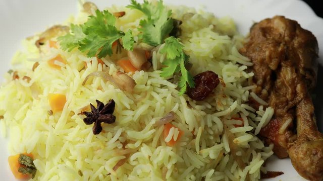 Chicken Biryani showing leg piece - It's a delicious recipe of Basmati rice mixed with with spicy marinated chicken in a bowl. Served in a bowl or plate. Selective focus	