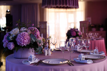 table setting in a restaurant in pink color, festive dinner, a bouquet of pink flowers is on the table,