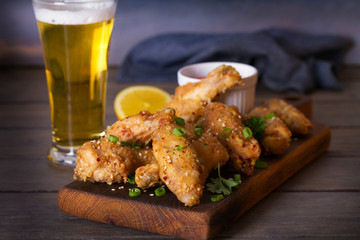 Chicken wings on serving board and glass of beer