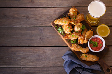 Chicken wings on serving board and glass of beer. View from above, top view. Copy space