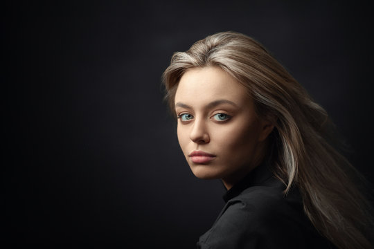 Dramatic studio portrait of beautiful young woman on dark background.