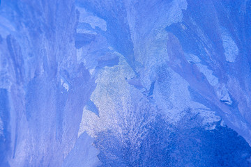 patterns on glass, frosty drawings in winter on a window, blue background and ice drawings,...