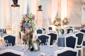 decor in the restaurant , floristic decoration of the festive table, a large vase with bright flowers, a festive dinner in honor of the wedding, table setting before dinner