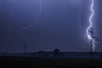Lightning bolts strike from a thunderstorm at night. Thunderstorm in the field. Spring and summer storm. Danger nature.