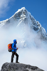 Tourist with a backpack and mountain panorama. Young man trekking in the mountains