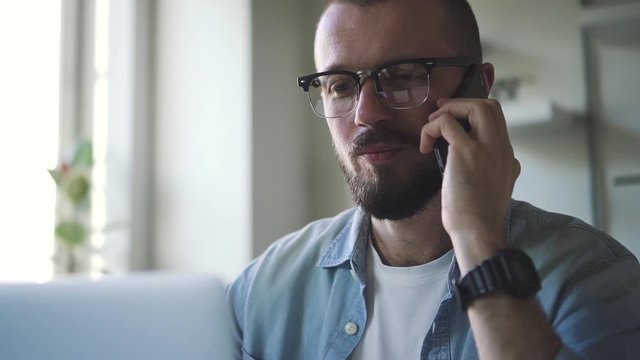 handsome man manager in glasses talking on the phone in office with laptop computer. Spbd remote work for the company. quarantined, remote worker at home discussing plans for cooperation.