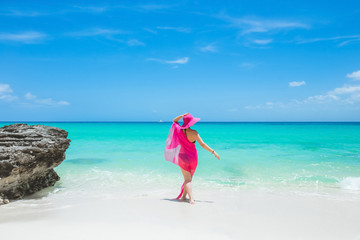 Woman enjoying sunny day on the tropical caribbean sandy beach landscape with turquoise sea and blue sky 