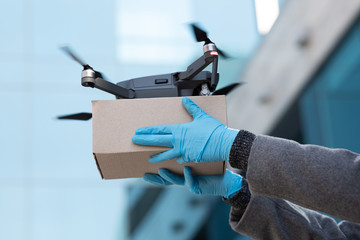 Modern drone delivering small box to customer, copy space