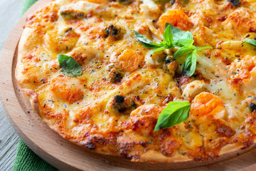 Seafood thin tasty pizza with shrimps, mussels and basil on wooden background