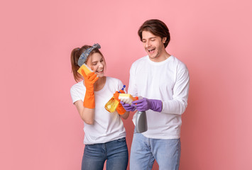 Crazy Cleaning. Joyful couple using sponges like cellphones, having fun during tidying