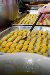 process making kastengels, an eid cookie, covered with egg yolk using brush