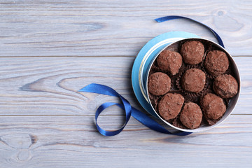 Box with tasty chocolate truffle candies on wooden table, flat lay. Space for text