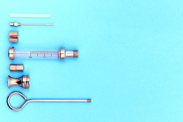 antique syringe disassembled into details on a blue background