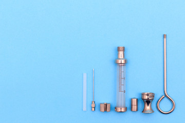 antique syringe disassembled into details on a blue background