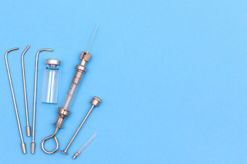 vintage syringe for intrauterine infections and tonsillectomy on a blue background. next to it ampoule empty. copyspace