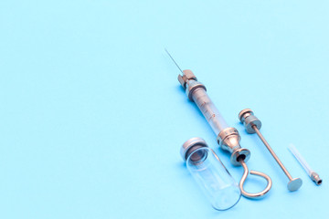 antique syringe made of metal and glass on a blue background. free space for text. copyspace
