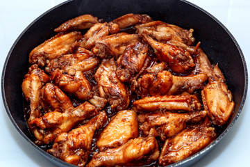 lots of fried chicken wings in a pan. close up