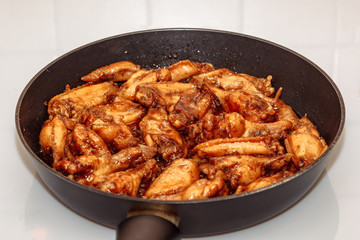 lots of fried chicken wings in a pan on a white ceramic plate. home cooking