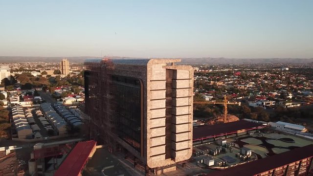 4K aerial drone summer sunrise video of Windhoek red brick large office building in city center in Namibia's capital in central highland Khomas Hochland of Namibia, southern Africa