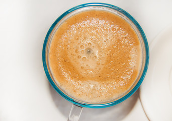 Top view of a blue glass coffee Cup, on a white background, hot frothy coffee