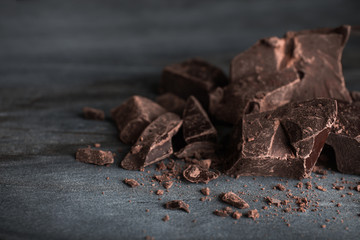 Pieces of dark chocolate on blue marble table, closeup