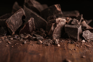 Pieces of dark chocolate on wooden table, closeup