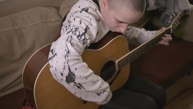 Concentrated Young Caucasian Man Playing Acoustic Guitar. - High angle shot