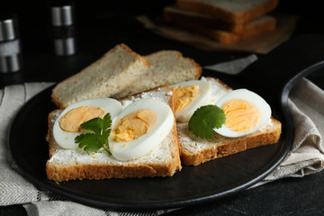 Tasty sandwiches with boiled eggs on slate board, closeup