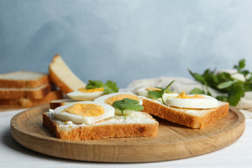 Tasty sandwiches with boiled eggs on wooden tray, closeup