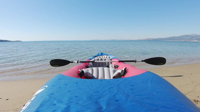 Tandem inflatable kayak and oar on sandy beach by sea on sunny day, static