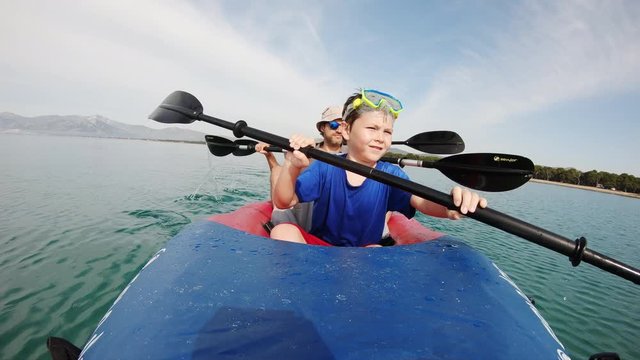 Young Caucasian boy paddling in front seat of tandem kayak, static portrait