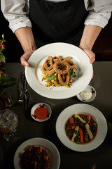 Chef presenting onion rings on dark background