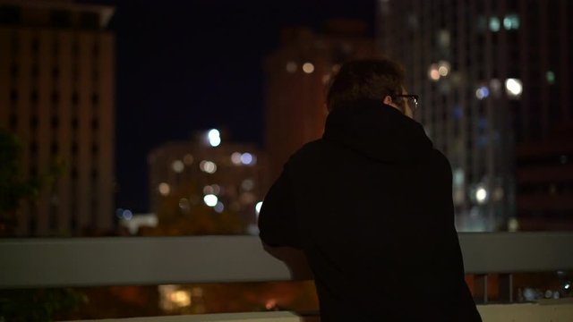 4K footage of man overlooking a city at night.