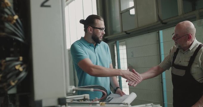 Two collaborators shake hands at the factory and inspect plastic window machine