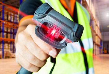 closeup worker holding bar code scanner with scanning red laser, warehouse inventory management.