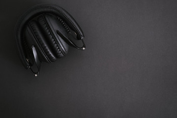 Black folded headphones on a black background.