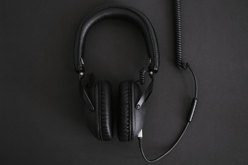 Black headphones with wire on a black background.