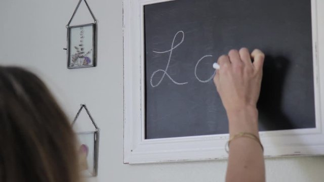 Women Writing "love" on a Blackboard with Chalk in Baby's  Nursery 