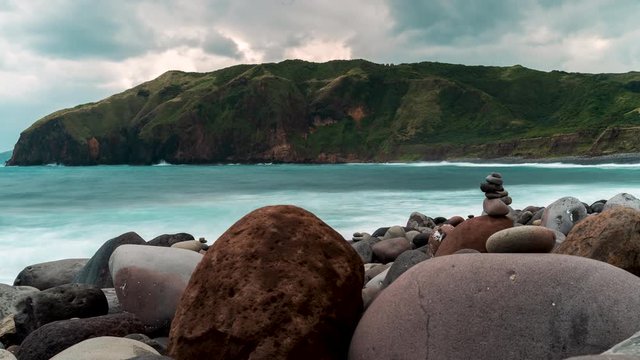 Time lapse of the sea with strong waves crashing to the rocky beach and the tall cliffs