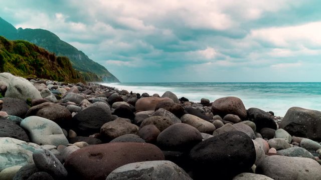 Time lapse of the sea with strong waves crashing to the rocky shore on a cloudy day