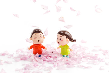 Obraz na płótnie Canvas Two dolls among the petals of the cherry blossom